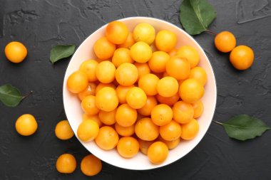 Olgun sarı kiraz erikleri ve yaprakları siyah masanın üzerinde, düz yatıyordu.