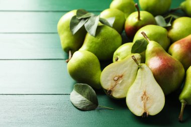 Taze armutlar ve yeşil ahşap masada yapraklar, yakın plan. Metin için boşluk
