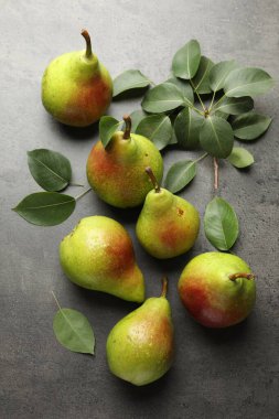 Taze olgun armutlar ve yeşil yapraklar gri masada, düz yatıyordu.
