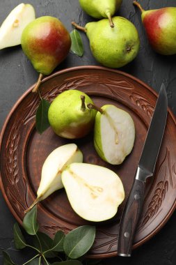 Taze armutlar, bıçak ve yeşil yapraklar siyah masada, düz yerde.