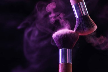 Siyah arka planda mor göz farlı makyaj fırçaları, yakın plan. Metin için boşluk