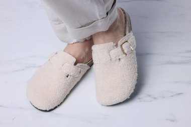 Beyaz mermer zeminde, yumuşak terlikli kadın, yakın plan.