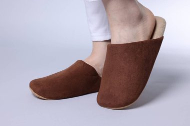 Gri arka planda yumuşak kahverengi terlikli kadın, yakın plan.