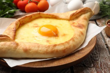 Lezzetli khachapuri peyniri, yumurtası ve diğer ürünleri ahşap masada, yakın plan.