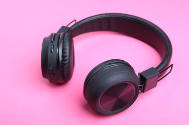 Pembe arka planda bir çift siyah kulaklık.