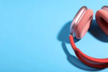 Açık mavi arka planda bir çift şık pembe kulaklık. Metin için boşluk