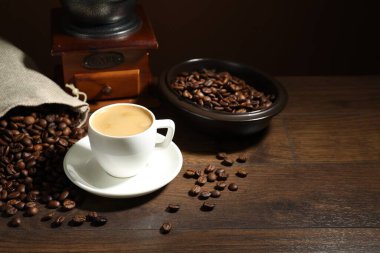 Aromatik kahve fincanda, fasulye ve öğütücü ahşap masada, mesaj için yer