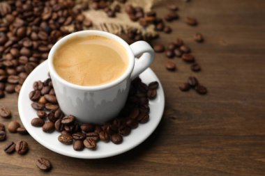 Aromatik kahve fincanda, fasulye de ahşap masada, yakın plan. Metin için boşluk