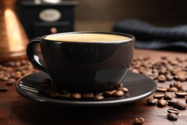 Aromatik kahve fincanda ve fasulyeler ahşap masada, yakın plan.