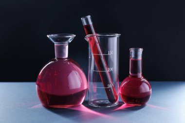 Siyah zemin üzerinde kırmızı sıvı bulunan laboratuvar camları