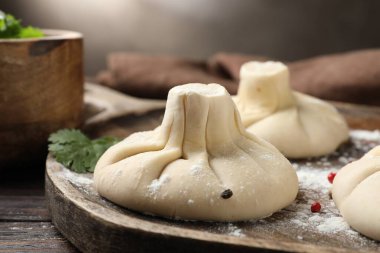 Ahşap masada biberli ve maydanozlu pişmemiş khinkaliler (hamur tatlısı), yakın plan.