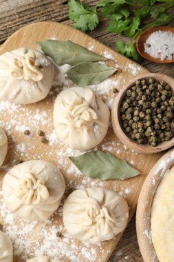 Biber, un, maydanoz ve defne yapraklarıyla ahşap masada pişmemiş khinkaliler (hamur köfteleri)