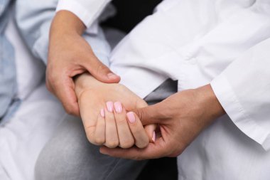 Doktor evde parmaklarıyla kadının nabzını kontrol ediyor.