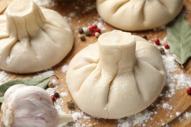 Biber, un ve defne yapraklarıyla pişirilmemiş khinkaliler (hamur köfteleri) ahşap masada, yakın plan