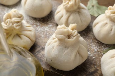 Ahşap masada un ve defne yapraklarıyla pişirilmemiş khinkaliler (hamur tatlısı), yakın plan.