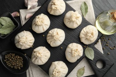 Biber, sarımsak ve defne yapraklarıyla pişirilmemiş khinkali (hamur köfteleri) siyah masada, düz yatar.