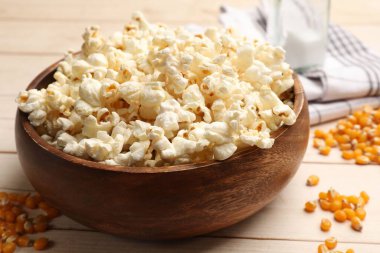 Lezzetli patlamış mısır ve mısır taneleri açık ahşap masada, yakın plan.