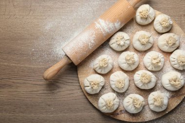 Pişmemiş khinkaliler (hamur köfteleri) ve ahşap masa üzerinde merdane, üst manzara. Metin için boşluk