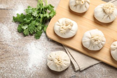 Tahta masada pişmemiş khinkalis (hamur tatlısı) ve kişniş, düz konum