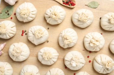 Pişmemiş khinkaliler (hamur tatlısı) ve ahşap masa üzerindeki baharatlar, düz konum