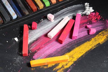 Siyah arkaplanda birçok renkli tebeşir pastelleri