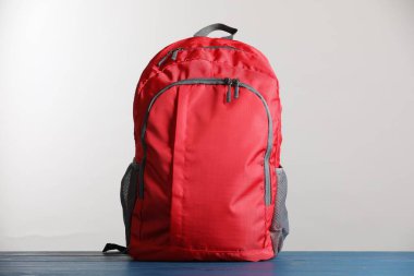 Kırmızı okul sırt çantası mavi ahşap masada açık gri arka planda