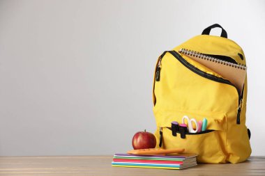 Sarı sırt çantası, kırtasiye ve kırmızı elma açık gri arkaplan, metin için boşluk