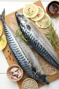 Taze çiğ uskumrular ve baharatlar beyaz ahşap masada, düz yerde. Deniz ürünleri lezzetleri.