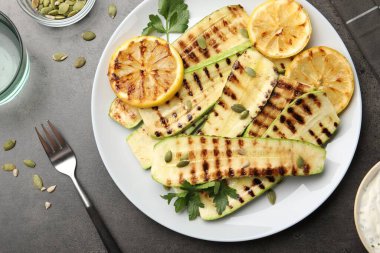 Gri desenli masada servis edilen balkabağı tohumlu, limonlu ve maydanozlu lezzetli kabak dilimleri.