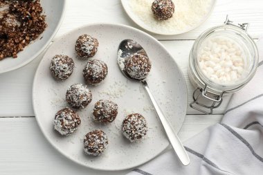 Fındıklı çikolatalı şekerler, hindistan cevizli gevrekler ve beyaz ahşap masada pilav.