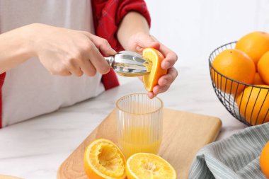 Meyve suyu. İçerideki beyaz mermer masada portakal suyu kullanan kadın, yakın plan.