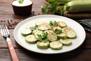 Ahşap masada servis edilen maydanozlu lezzetli kabak dilimleri, yakın plan.