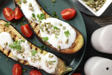 Patlıcan dilimleri, balkabağı çekirdekleri, domates ve yoğurt, ahşap masa, düzlük.