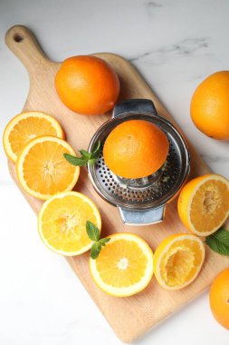 Portakallı sıkma makinesi ve beyaz masa üzerinde nane şekeri. Taze meyve suyu.