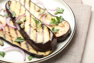 Izgara patlıcan, maydanoz, kabak çekirdeği ve soğan dilimleri, yakın plan.