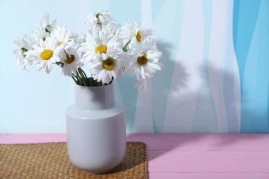 Vazodaki güzel papatya çiçekleri pembe ahşap masada, arka planda, yakın plan. Metin için boşluk