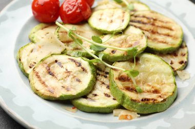 Lezzetli ızgara kabak dilimleri, domatesler ve tabakta mikroyeşiller, yakın plan.