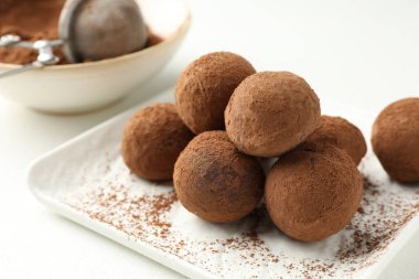 Beyaz masa üzerinde kakao tozu olan lezzetli çikolata şekerlemeleri, yakın plan.