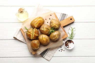 Beyaz ahşap masada servis edilen biberiyeli lezzetli fırında patatesler.