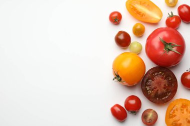 Beyaz masada farklı olgun domatesler, düz uzanmış. Metin için boşluk