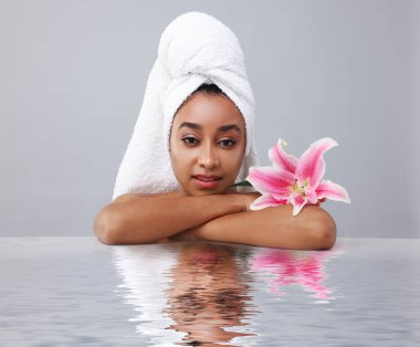 Mükemmel ciltli güzel bir kadın ve gri arka planda zambak çiçeği. Dalgalı sudaki yansıması