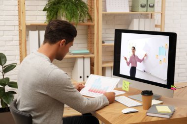 E-öğrenme konsepti. Öğrenci masadaki bilgisayar aracılığıyla öğretmenle çevrimiçi görüntülü sohbet ediyor