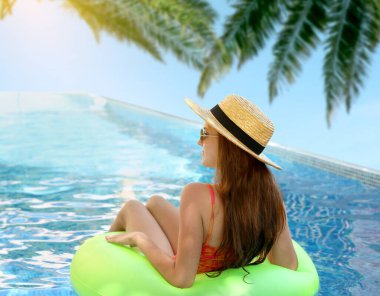 Yüzme havuzunda yüzen şişme yüzüklü bir kız.