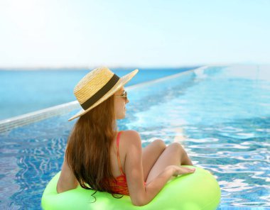 Yüzme havuzunda yüzen şişme yüzüklü bir kız.