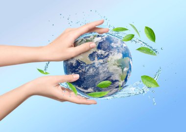 Su kavramını sakla. Dünya, kadının ellerinde mavi eğimli arka plana karşı, yakın plan. Su sıçrıyor ve dünyanın her yerinde yeşil yapraklar