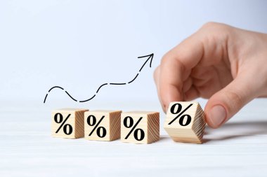 Beyaz masada üzerinde yüzde işareti olan tahta küpü tutan adam, yakın plan.