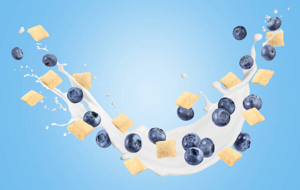 Splashing milk with sweet corn pads and fresh blueberries in air against light blue background. Healthy breakfast