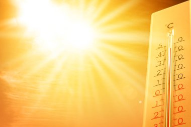 Güneşli bir günde, turuncu gökyüzüne karşı termometrede son derece yüksek sıcaklık. Şiddetli sıcak yaz havası