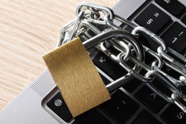 Siber güvenlik. Zincirli metal kilit ve dizüstü bilgisayar ahşap masa, üst görünüm