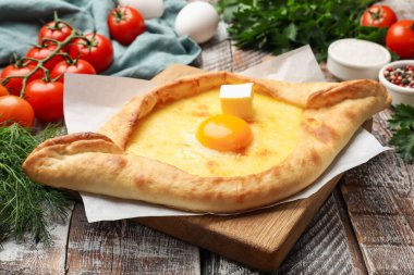 Lezzetli khachapuri peyniri, yumurtası ve diğer ürünleri ahşap masada, yakın plan.